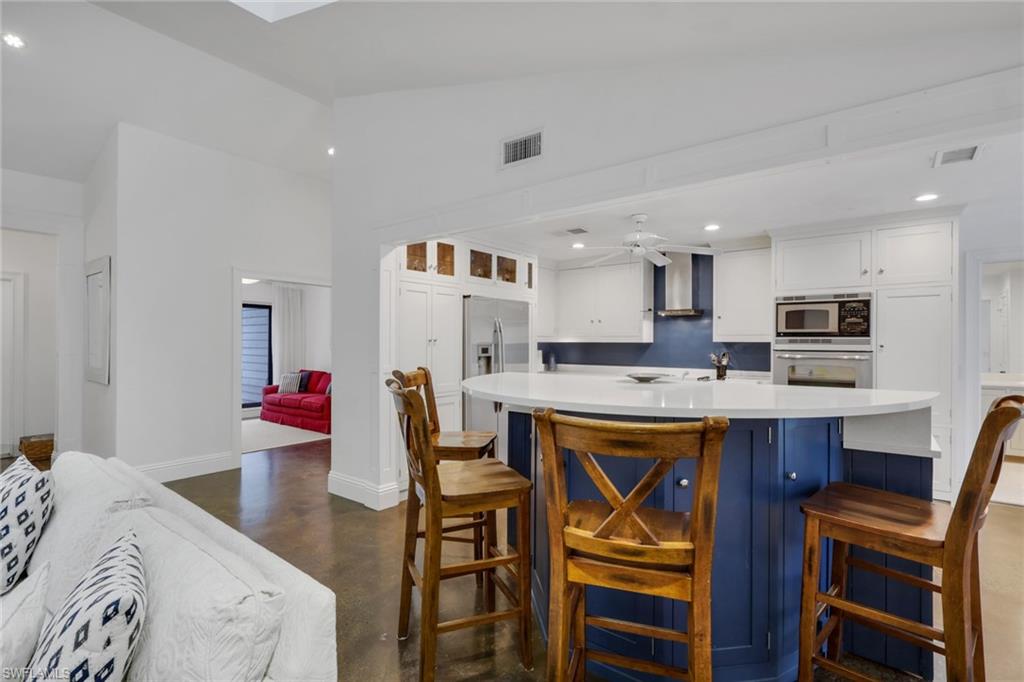 Kitchen featuring polished concrete flooring, a ceiling fan, a kitchen bar, stainless steel appliances, and recessed lighting