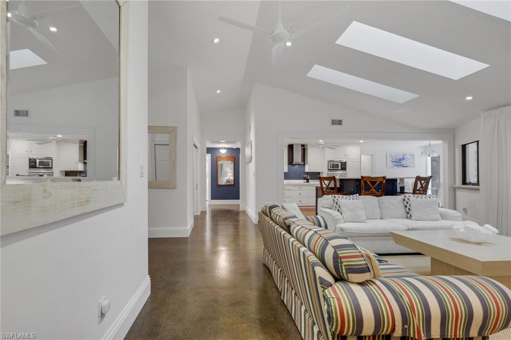 Living room with ceiling fan, polished concrete floors, vaulted ceiling, recessed lighting, and a skylights