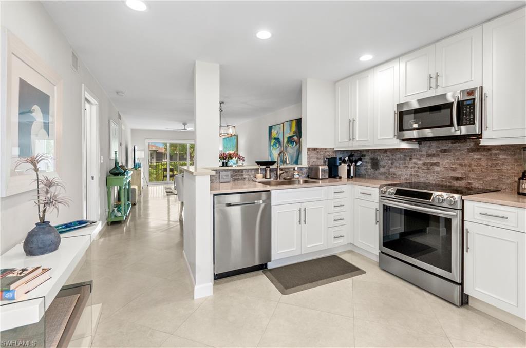 Kitchen featuring stainless steel appliances, a peninsula, white cabinets, recessed lighting, and backsplash