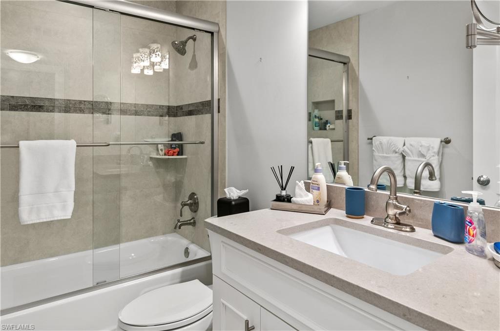 Bathroom featuring vanity and bath / shower combo with glass door