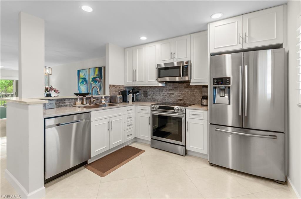 Kitchen featuring stainless steel appliances, white cabinetry, a peninsula, recessed lighting, and light tile patterned floors
