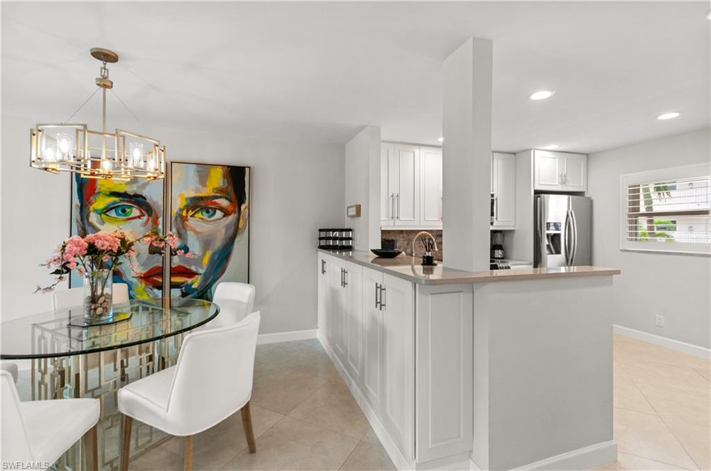 Kitchen featuring stainless steel fridge with ice dispenser, white cabinetry, a peninsula, and light tile patterned floors
