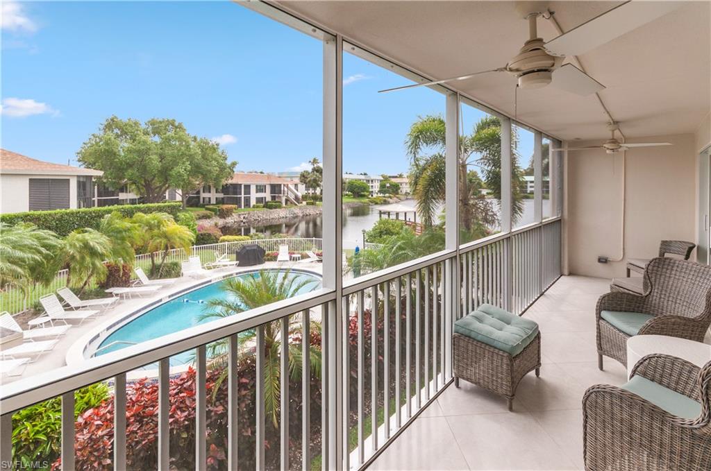 Balcony featuring view of pool area, ceiling fan, and a water view