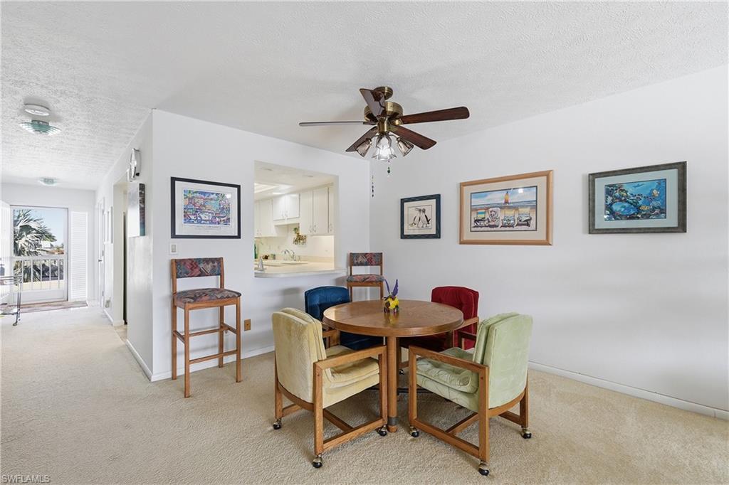 Dining room featuring a textured ceiling, light carpet, and ceiling fan