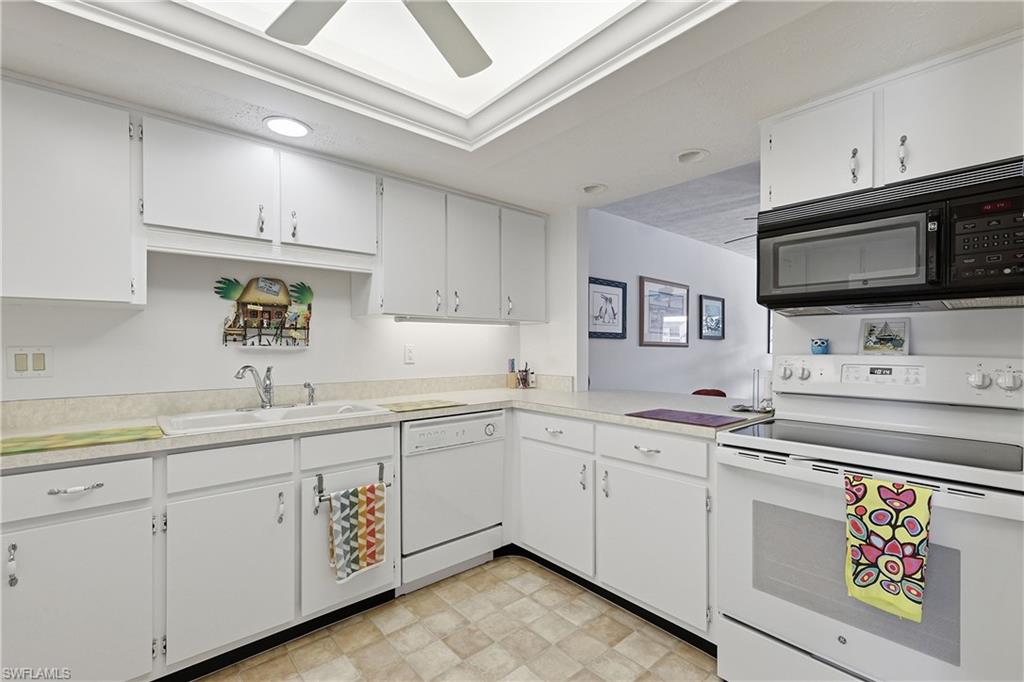 Kitchen featuring white appliances, light countertops, and white cabinets