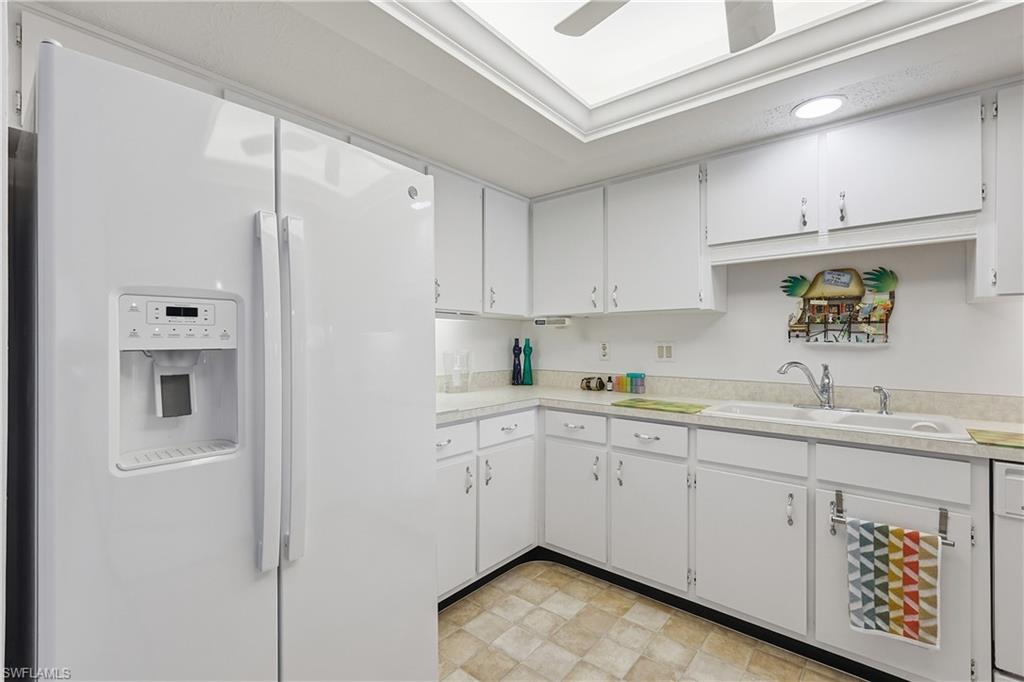 Kitchen with white appliances, light countertops, and white cabinetry