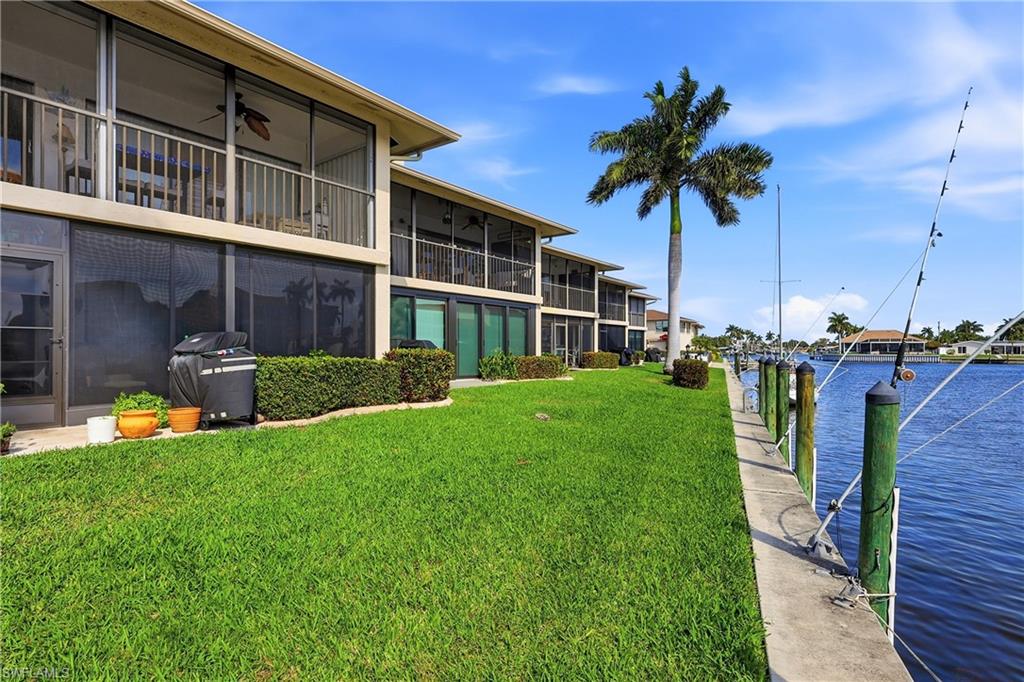 Dock area with a yard, a water view, and a sunroom