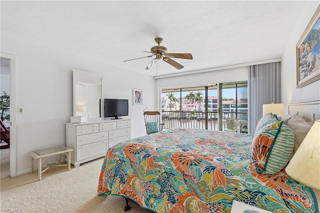Bedroom featuring access to exterior, a ceiling fan, light colored carpet, and a textured ceiling