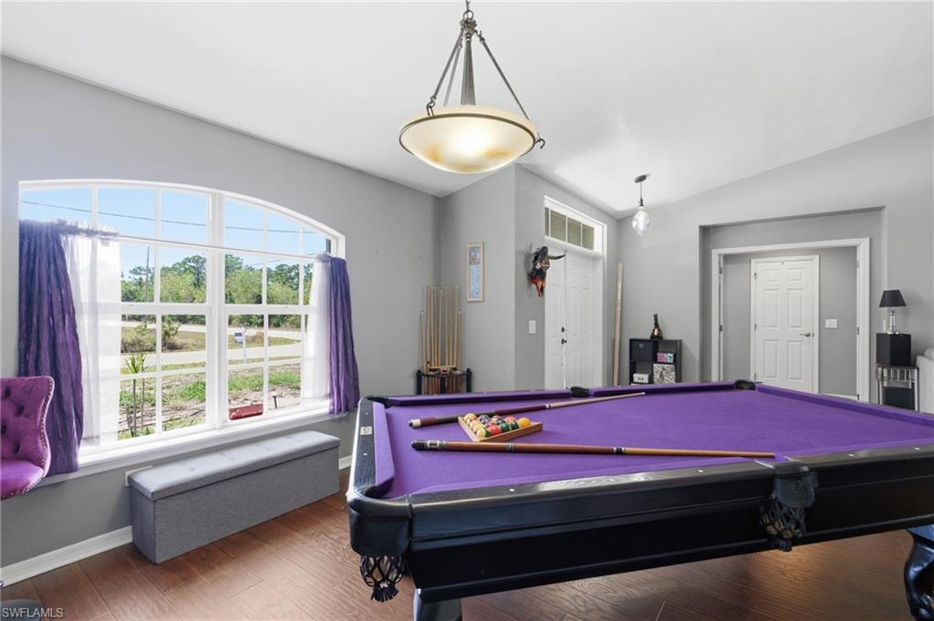 Game room with dark wood finished floors, vaulted ceiling, healthy amount of natural light, and pool table