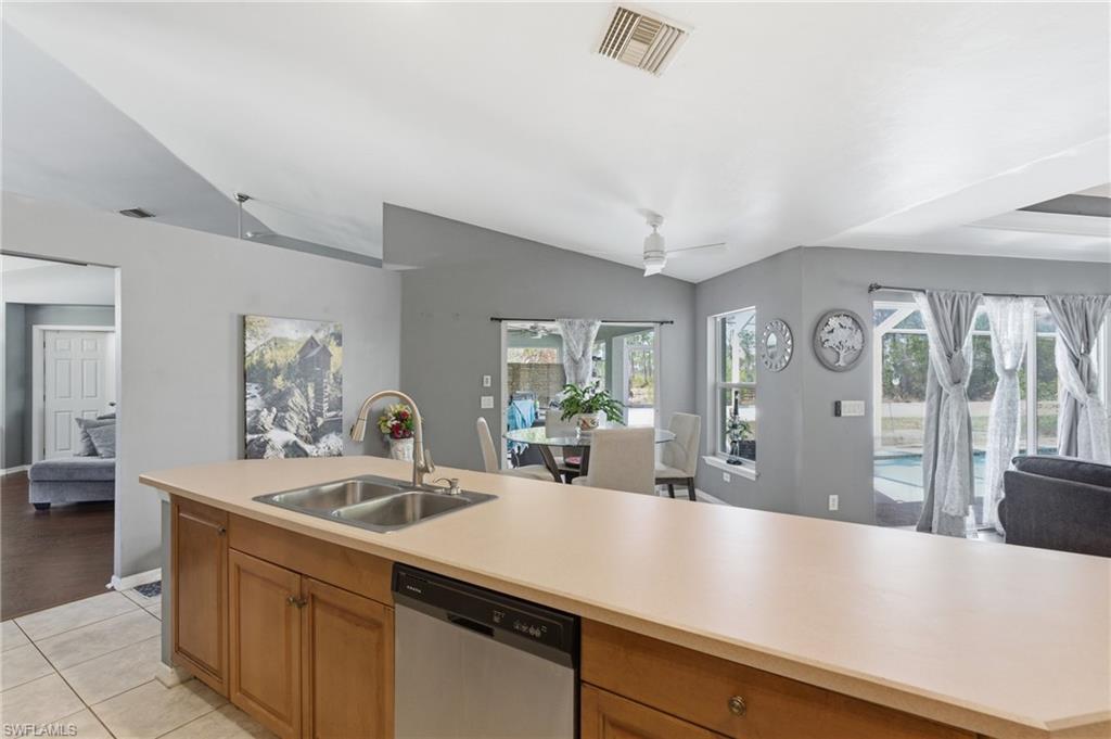 Kitchen with open floor plan, light countertops, dishwasher, vaulted ceiling, and healthy amount of natural light
