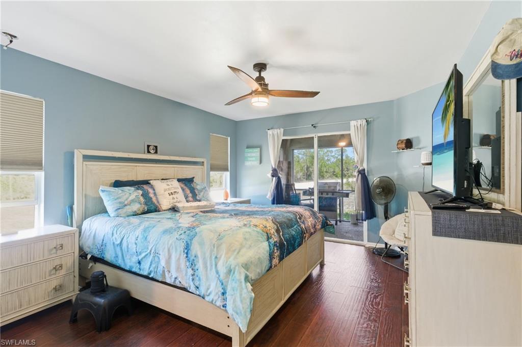 Bedroom with access to outside, dark wood-type flooring, and a ceiling fan