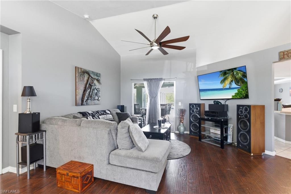 Living room featuring ceiling fan, dark wood-style floors, and lofted ceiling