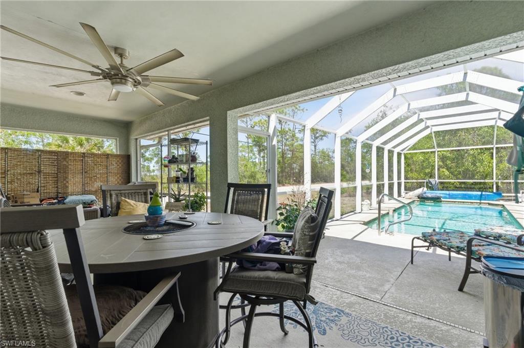 Sunroom featuring a patio, outdoor dining space, a ceiling fan, and a swimming pool