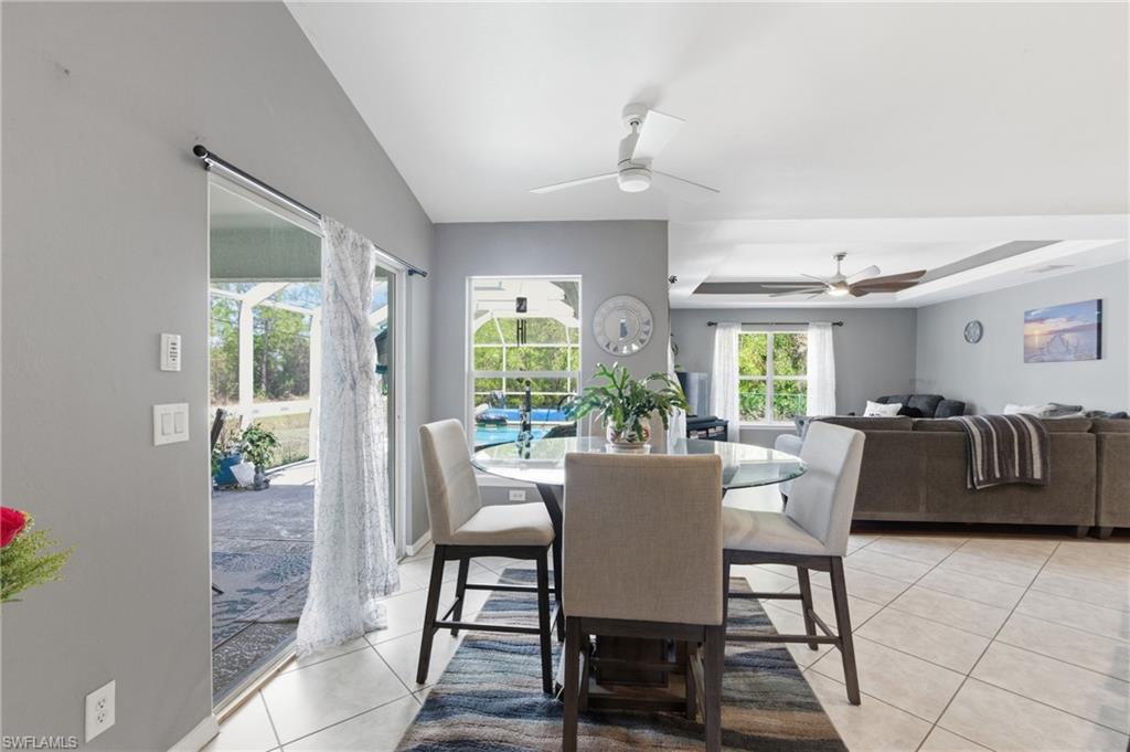 Dining room featuring a tray ceiling, light tile patterned floors, and a ceiling fan