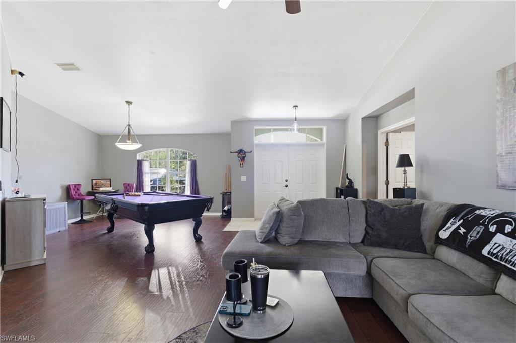 Living room with billiards table, dark wood-type flooring, lofted ceiling, and ceiling fan