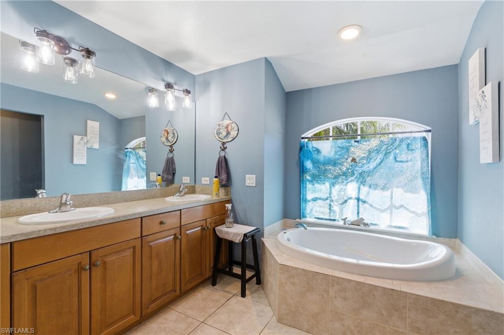Full bathroom with double vanity, light tile patterned floors, a garden tub, and recessed lighting