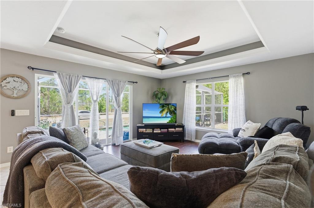 Living room featuring a ceiling fan and a raised ceiling
