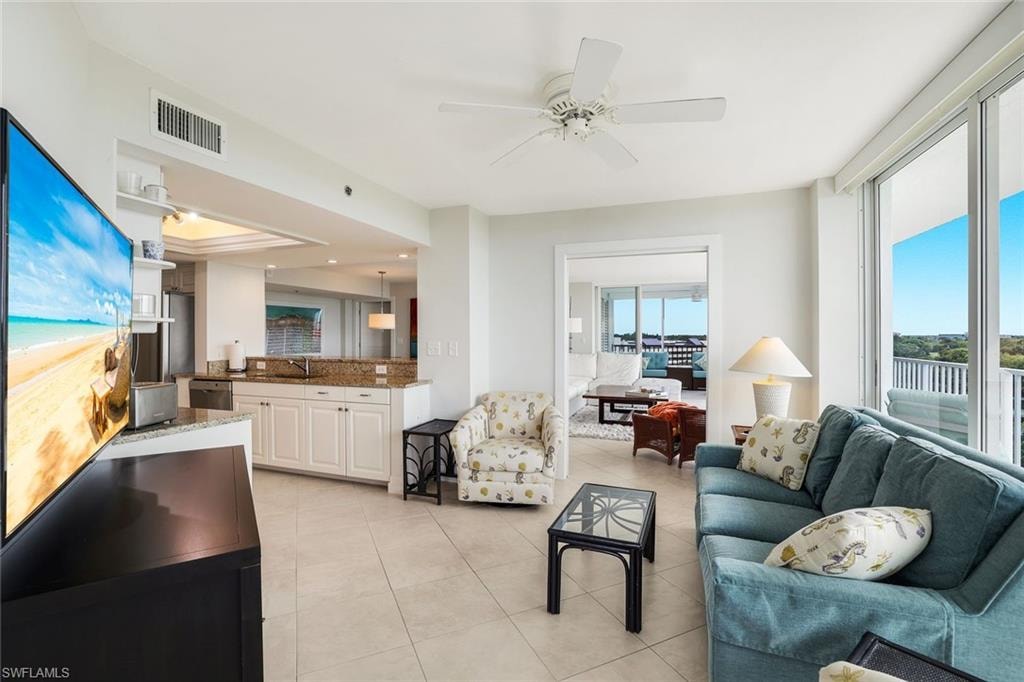 Living area featuring a ceiling fan, light tile patterned floors, and a tray ceiling