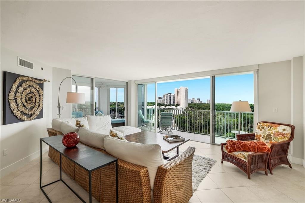 Living area with floor to ceiling windows, light tile patterned floors, and a city view