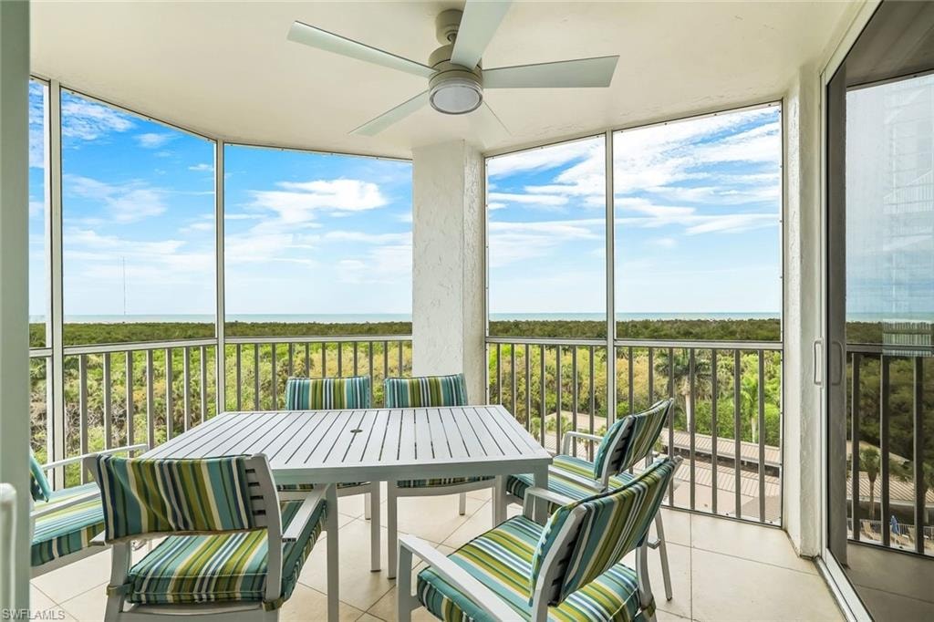 Sunroom / solarium featuring ceiling fan, a balcony, outdoor dining space, and a water view