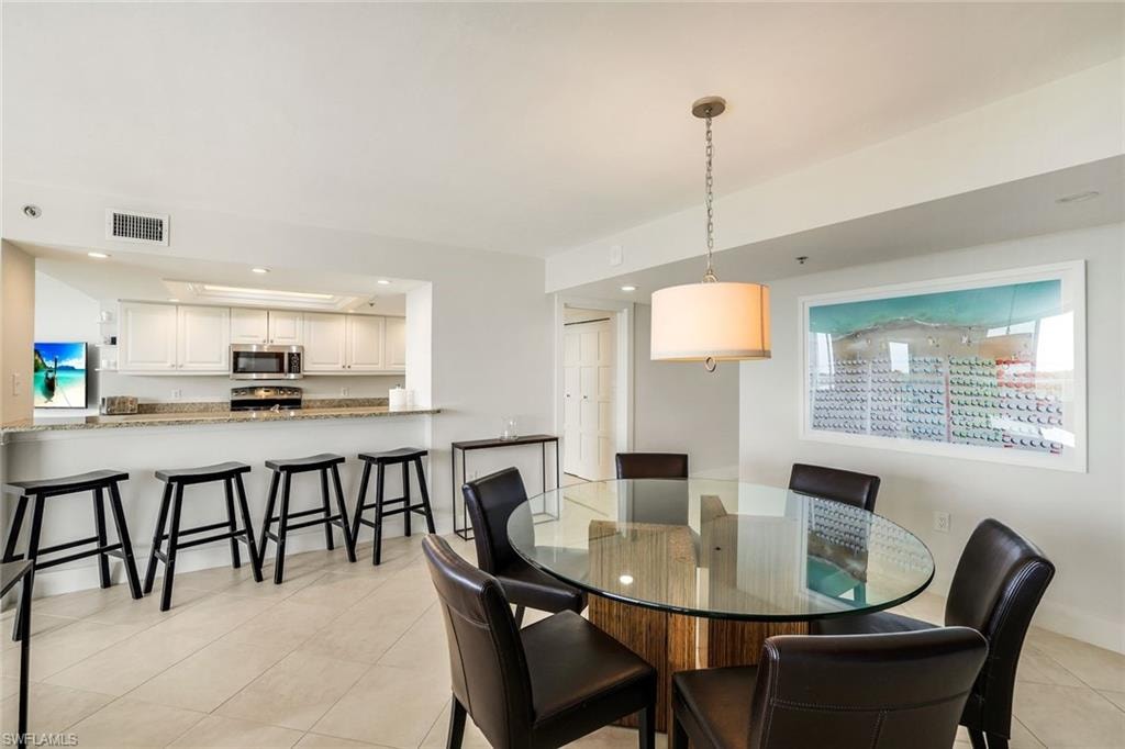 Dining space with light tile patterned floors and recessed lighting