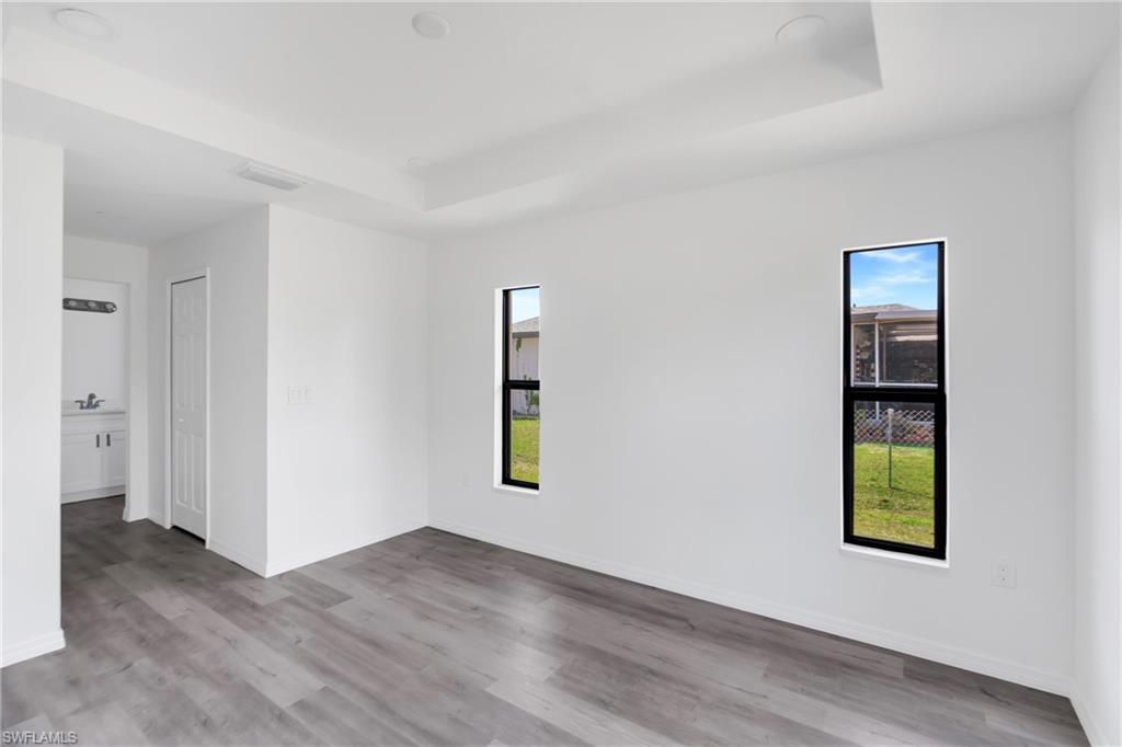 Spare room featuring a raised ceiling, plenty of natural light, light wood-type flooring, and recessed lighting