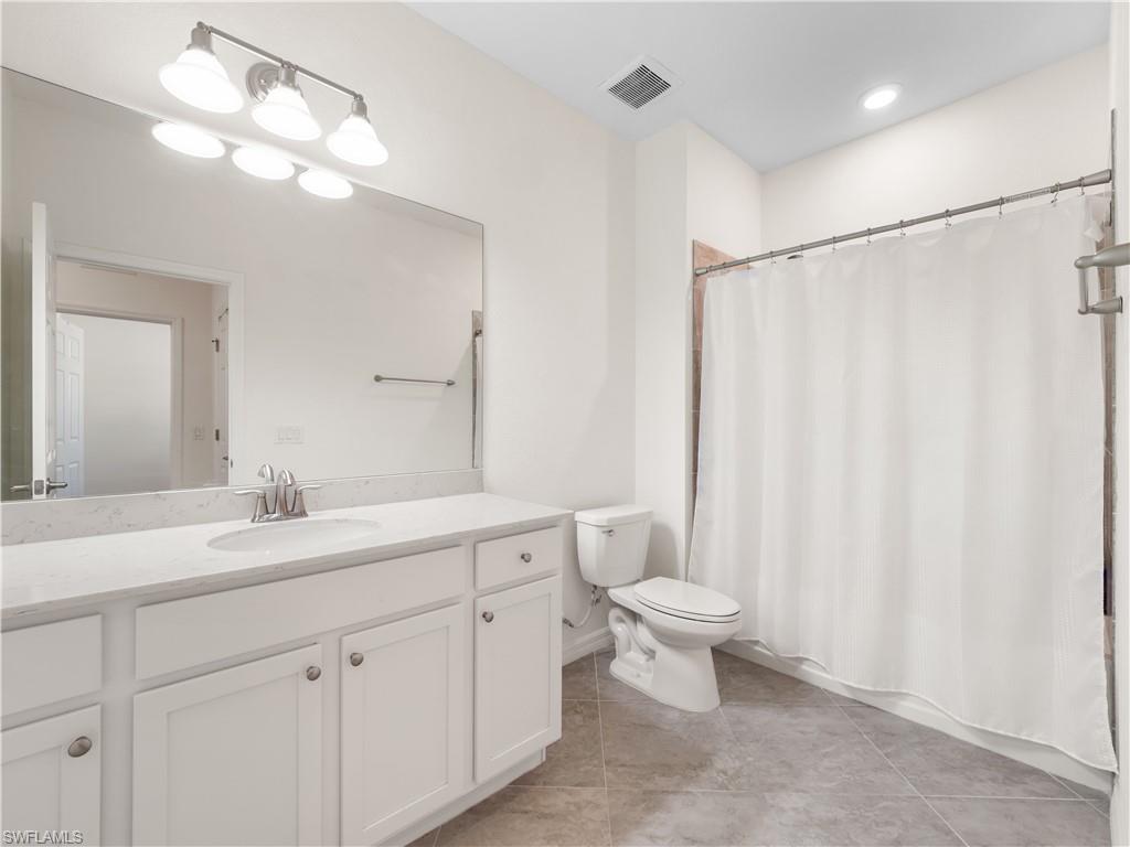 Bathroom with curtained shower, vanity, and light tile patterned floors