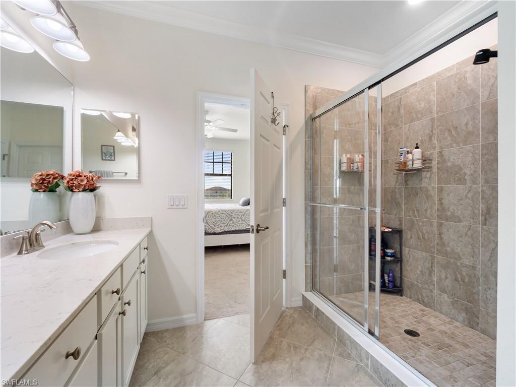 Bathroom with vanity, ensuite bathroom, a shower stall, crown molding, and light tile patterned flooring