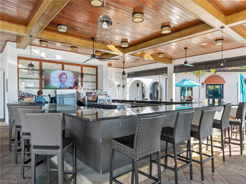 Kitchen featuring a wooden ceiling with exposed beams, pendant lighting, a kitchen bar, and dark stone counters
