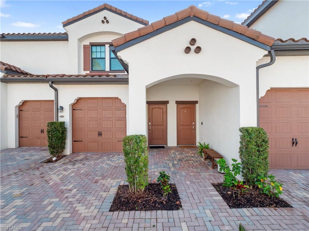 Mediterranean / spanish-style house featuring a tiled roof, a garage, stucco siding, and decorative driveway
