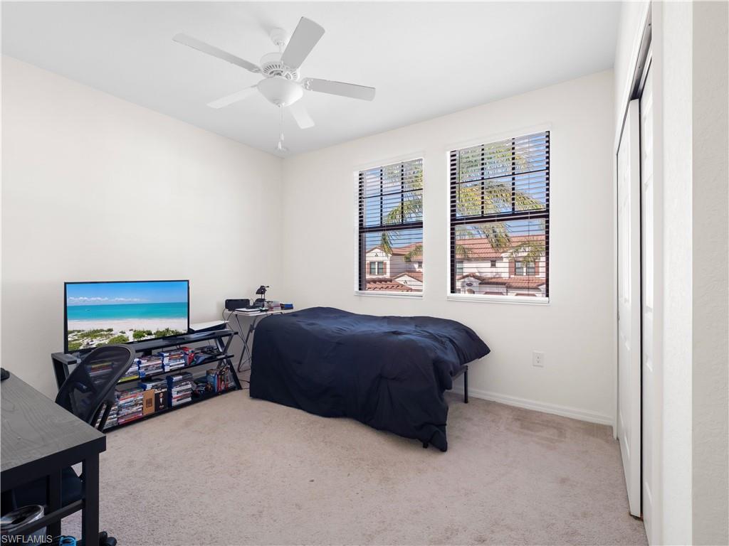 Bedroom with carpet, ceiling fan, a desk, and a closet