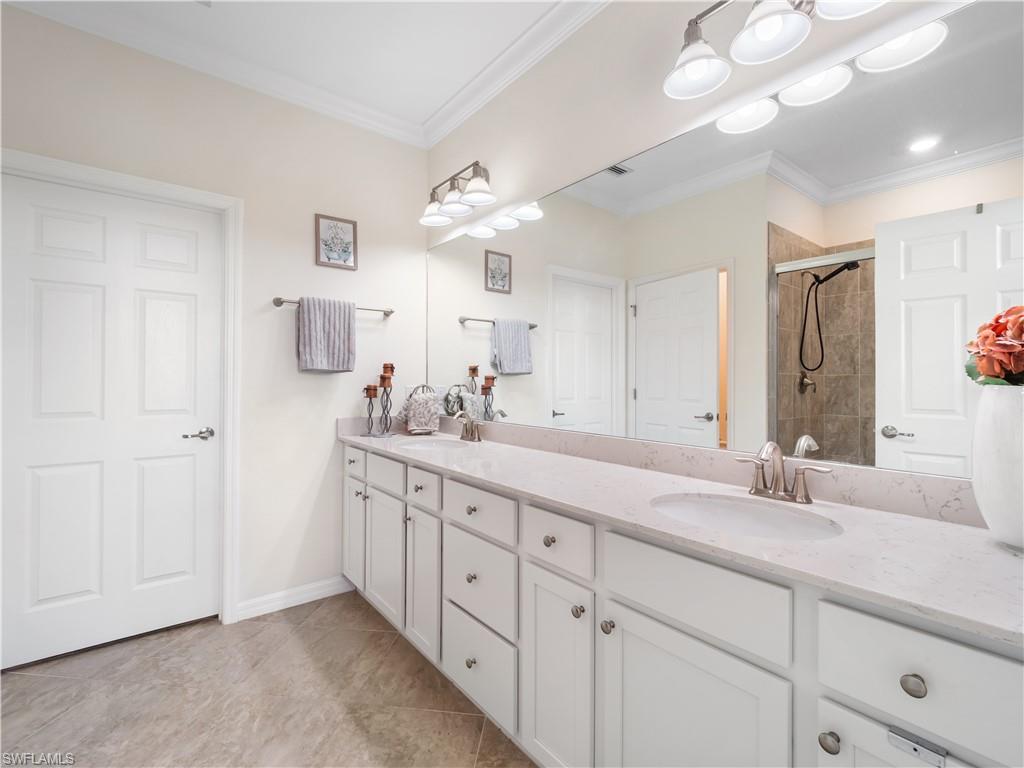 Full bathroom with double vanity, crown molding, and a shower stall