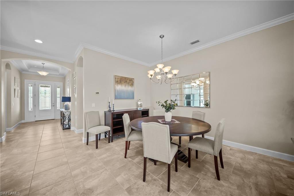 Dining room featuring arched walkways, suspended lighting, and ornamental molding