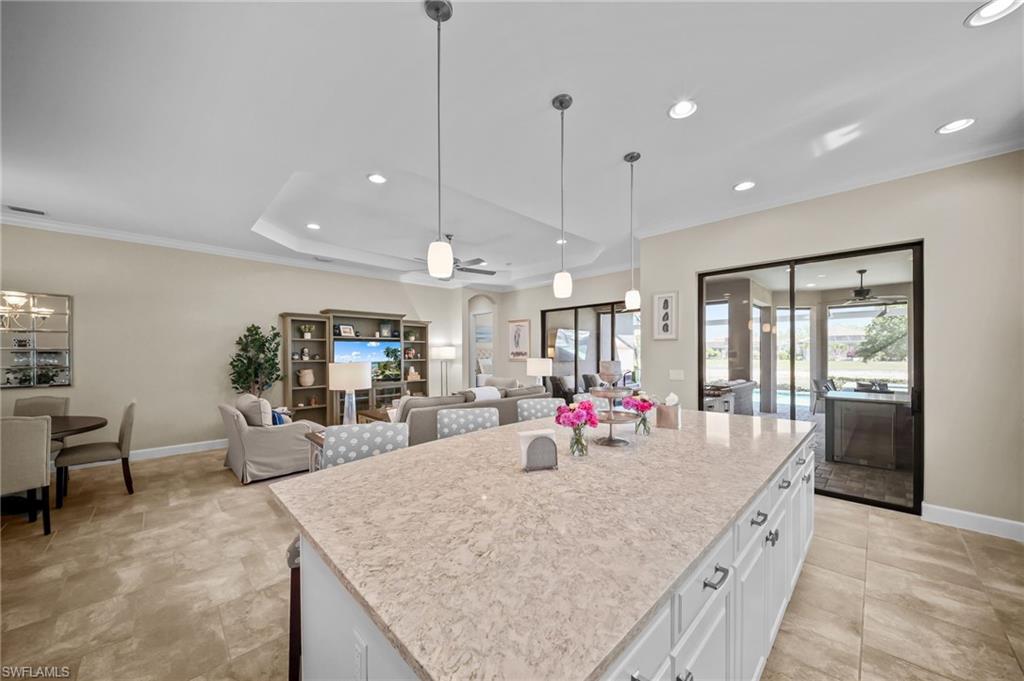 Kitchen with white cabinets, ceiling fan, open floor plan, a kitchen island, and pendant lighting