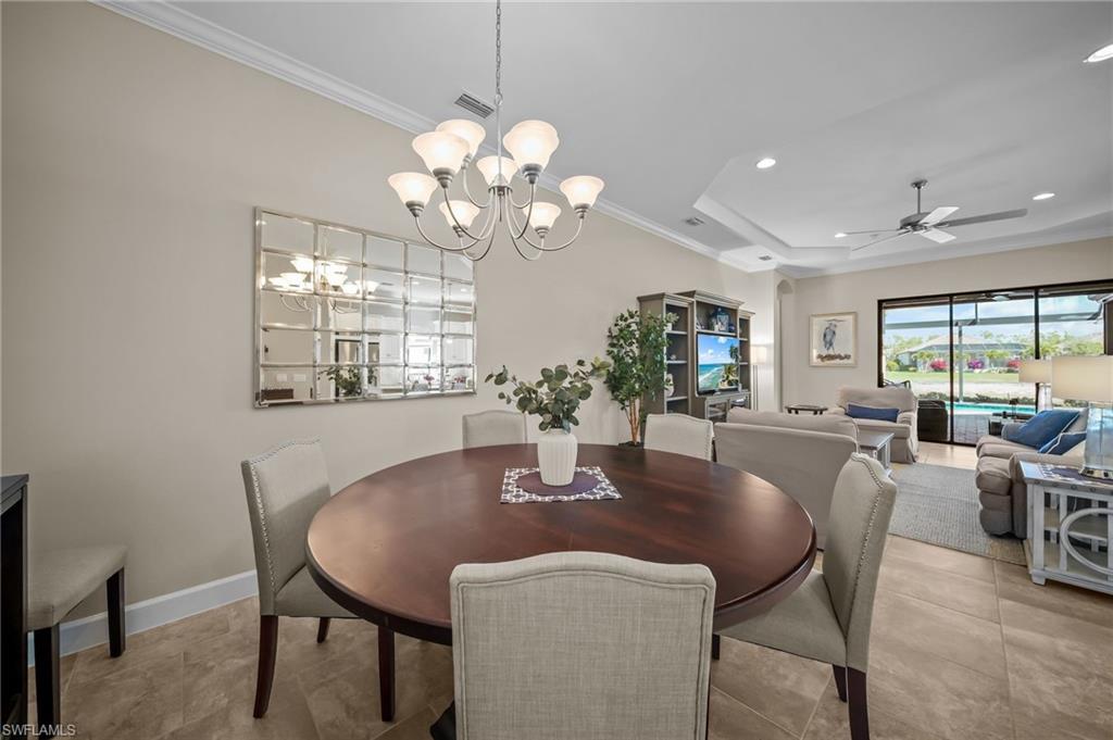 Dining space with ornamental molding, ceiling fan, hanging lights, and a tray ceiling