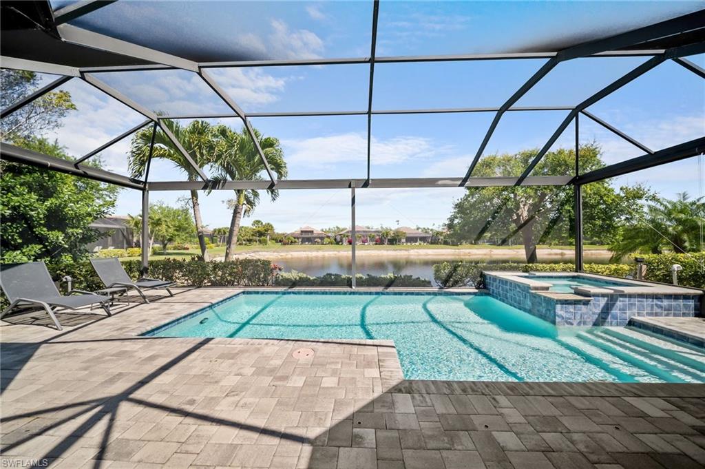 Integrated pool / spa with a sunroom, a patio, a water view, and glass enclosure