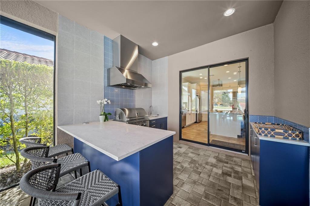 Kitchen featuring a kitchen breakfast bar, a peninsula, blue cabinets, tile walls, and recessed lighting
