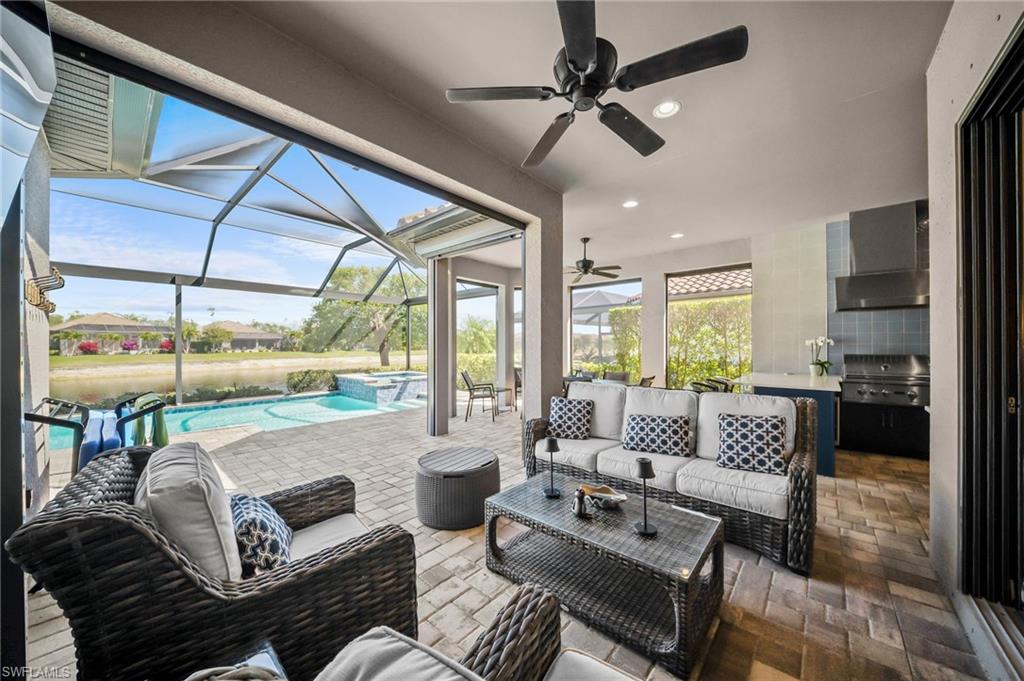 View of patio with a pool with connected hot tub, a ceiling fan, glass enclosure, and a sunroom