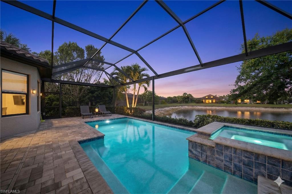 Combined pool / hot tub featuring a sunroom, glass enclosure, a patio area, and a water view