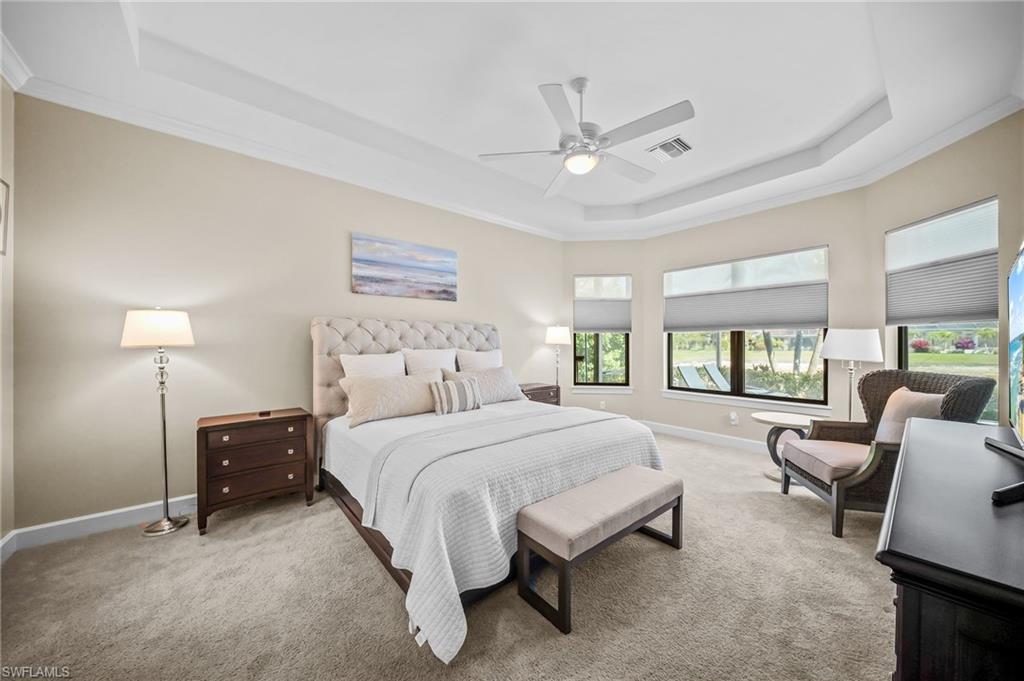 Carpeted bedroom with crown molding, a raised ceiling, and ceiling fan