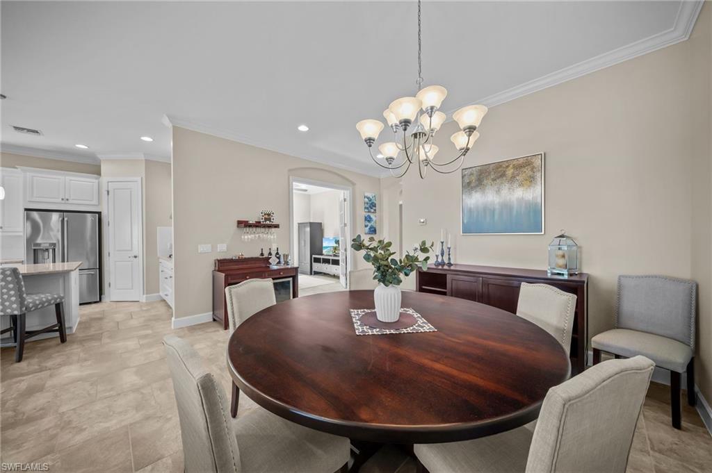 Dining room with arched walkways, ornamental molding, and suspended lighting