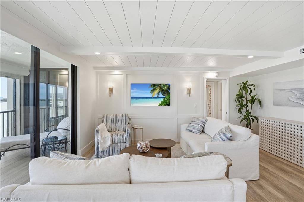 Living area with wood finished floors, a wood ceiling with exposed beams, and a decorative wall - Virtually Edited Image