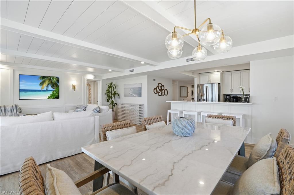 Dining room featuring light wood finished floors and beamed ceiling - Virtually Edited Image