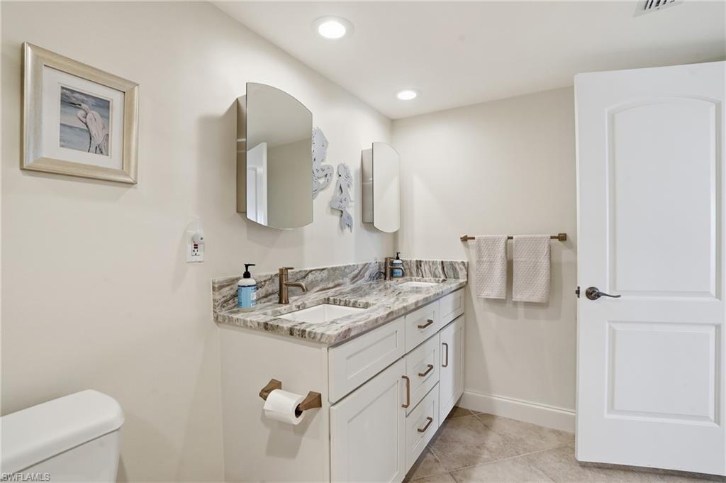 Full bath featuring double vanity, light tile patterned floors, and recessed lighting - Virtually Edited Image