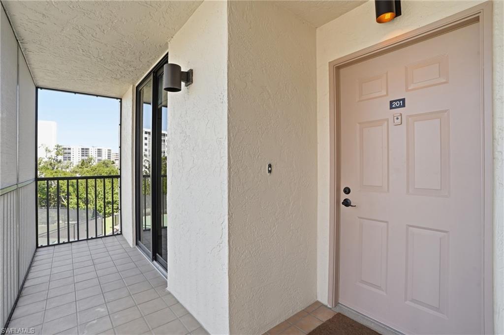 Property entrance featuring stucco siding and a sunroom - Virtually Edited Image