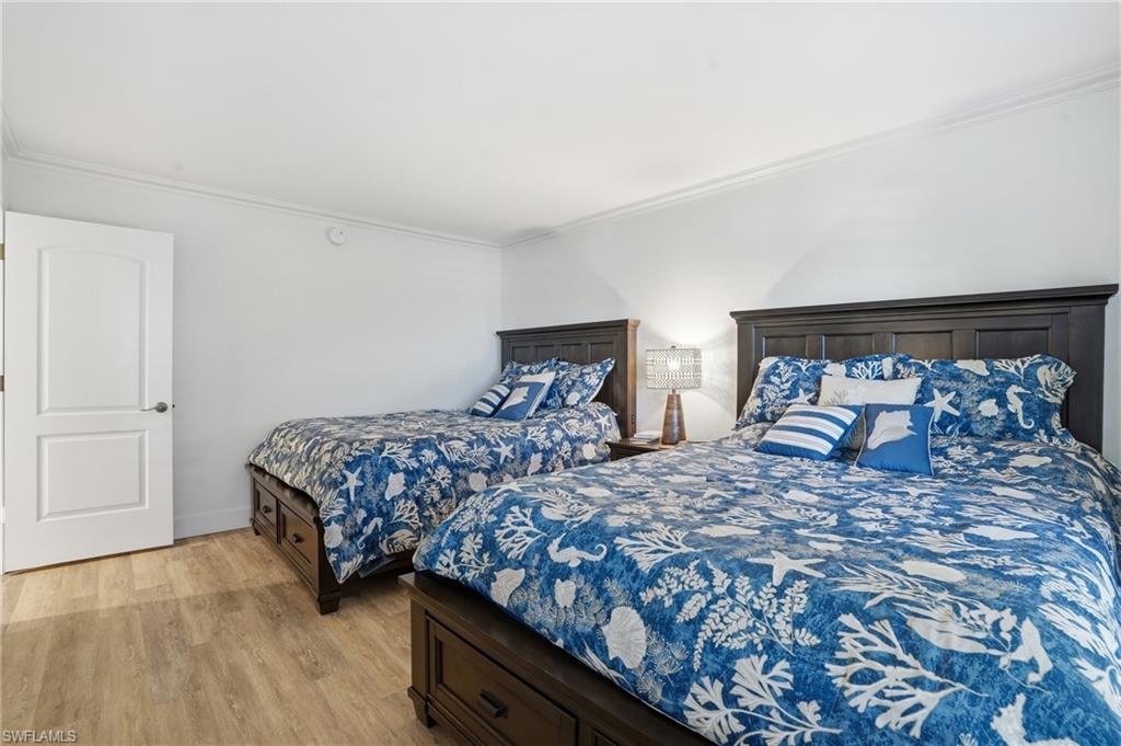 Bedroom with crown molding and light wood finished floors - Virtually Edited Image