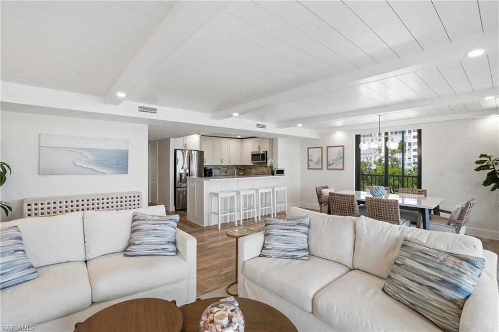 Living area with light wood-style floors, beamed ceiling, and suspended lighting - Virtually Edited Image