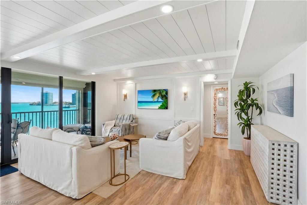 Living area with wood-finish flooring, shiplap ceiling, recessed lighting, and wall sconces - Virtually Edited Image