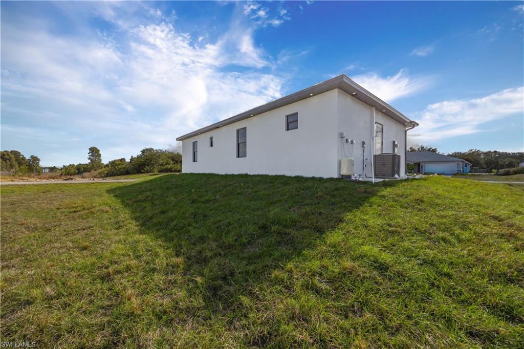 View of side of property featuring stucco siding and a lawn