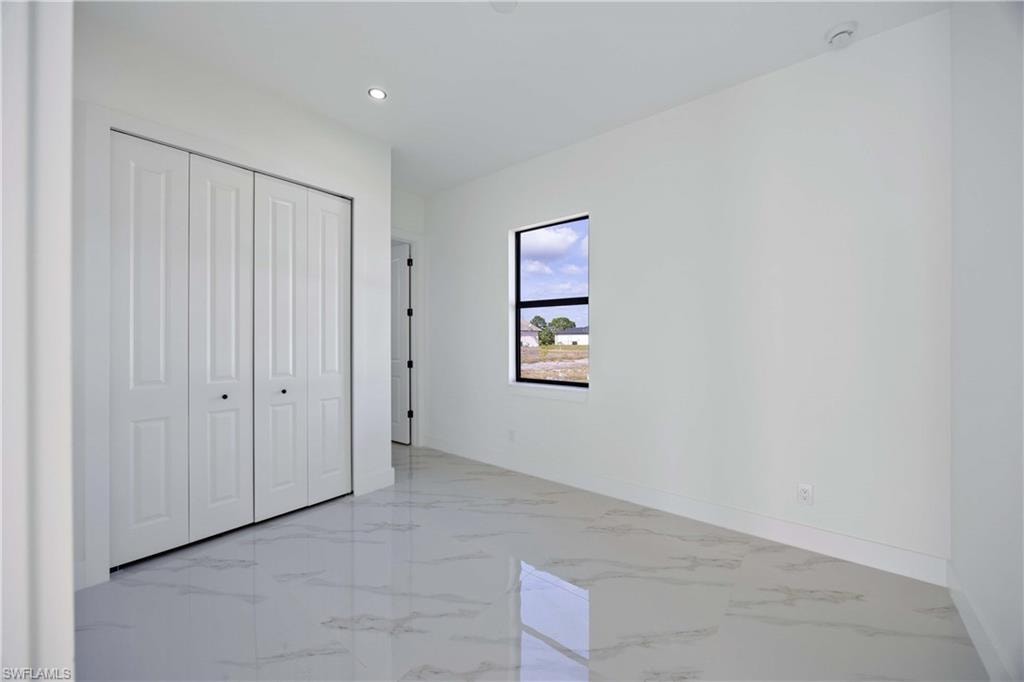 Unfurnished bedroom featuring a closet, light marble finish flooring, and recessed lighting